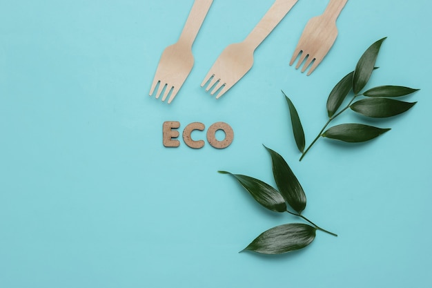 Foto concetto di cibo eco foglie verdi di forchette di legno su sfondo blu pastello vista dall'alto