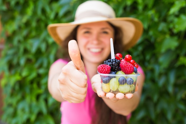 Eco food and healthy lifestyle concept - Portrait of smiling woman holding berries and showing thumb up gesture.