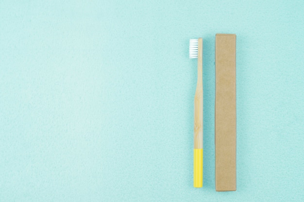 Eco-friendly bamboo toothbrush in paper packaging on a blue background