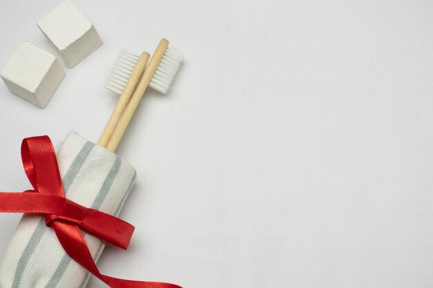 Eco friendly bamboo toothbrush with bathroom towel and red ribbon on white background