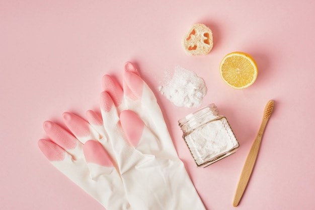 Eco friendly cleaning concept gloves bamboo toothbrush lemon and soda on pink background