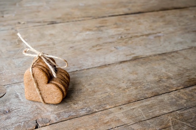 Eco friendly concept valentine's day flat lay. Cookies form of heatrs tied jute rope on a wooden background.