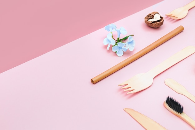 Eco friendly disposable utensils made of bamboo wood and paper on a isometric pink background. D