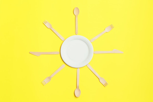 Eco-friendly disposable utensils made of bamboo wood on yellow background.