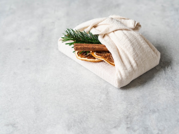 전나무 브런치, 계피 스틱 및 드라이 오렌지 슬라이스로 친환경 패브릭 재사용 가능한 선물 포장. 크리스마스 재사용 가능한 지속 가능한 선물 포장 대안. 폐기물 개념 제로.