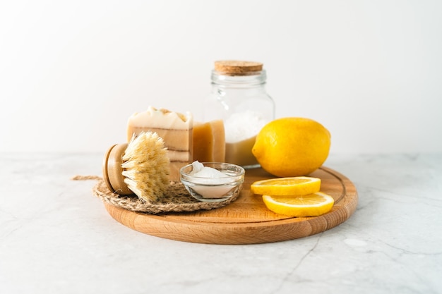 Eco friendly natural cleaners jar with baking soda dish brush lemon soap on white marble table