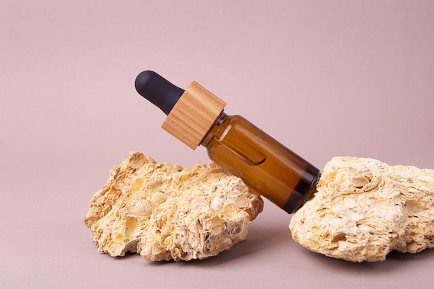 Eco friendly oil dropper with wooden cover on the natural stonesGood as cosmetics mockup