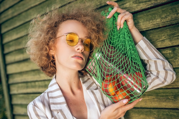 Eco friendly. Picture of a young woman in sunglasses with a mesh bag