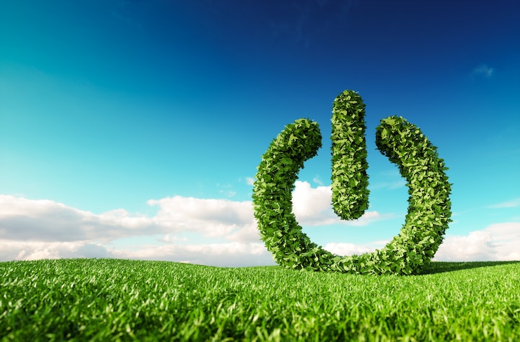 Photo eco friendly renewable energy concept. 3d rendering of green power button sign on fresh spring meadow with blue sky in background.