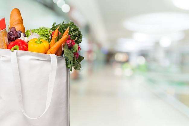 Eco friendly reusable shopping bag filled with vegetables on a blur background