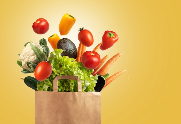 黄色の背景、コピースペースに野菜でいっぱいの環境に優しい再利用可能なショッピングバッグ