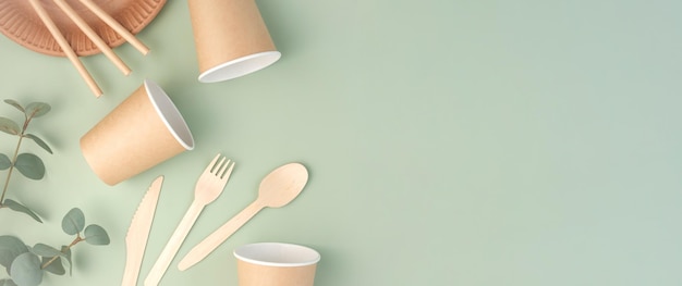 Eco friendly tableware on green background top view plastic\
free set of brown paper utensil street food recyclable packaging\
zero waste paperware mockup disposable take out cup wooden\
cutlery