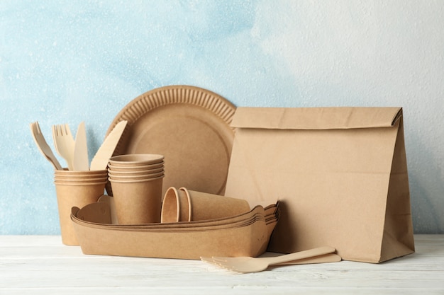 Eco - friendly tableware and paper bag on wooden table, space for text