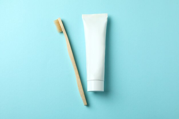 Eco friendly toothbrush and tube of toothpaste on blue