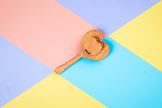 eco-friendly wooden toys, rattles in the form of a heart on pink, blue and yellow isolated background.  