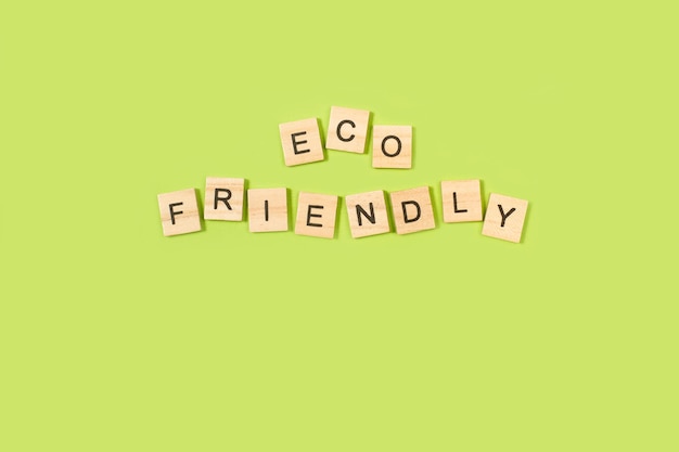 Eco Friendly написано деревянными буквенными блоками на зеленом фоне