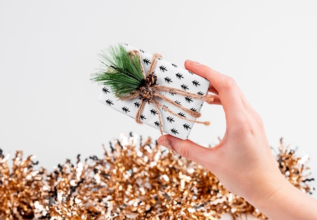 Eco geschenkdoos in handen en kerst glitter op witte achtergrond