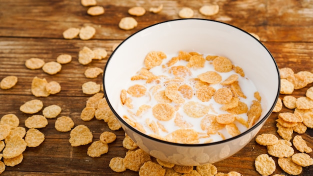 Foto superficie di cibo sano eco. fiocchi di mais con latte. fiocchi nel latte in una ciotola bianca. cibo sano e colazione fresca