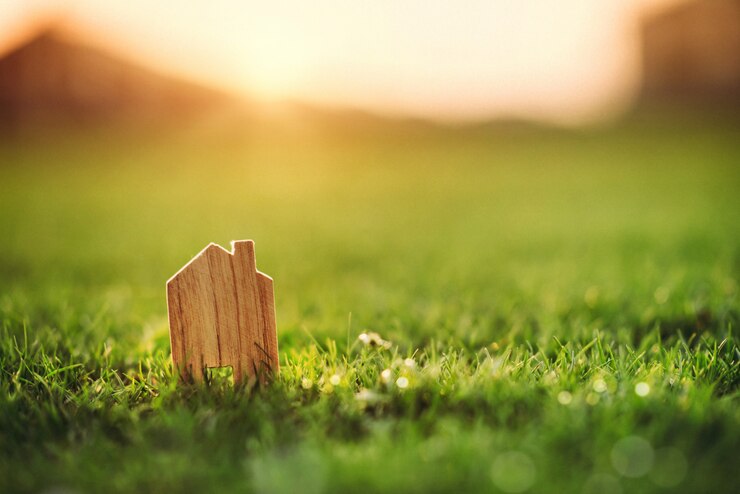 Eco house concept, Small model of home over green grass dueling sunset.
