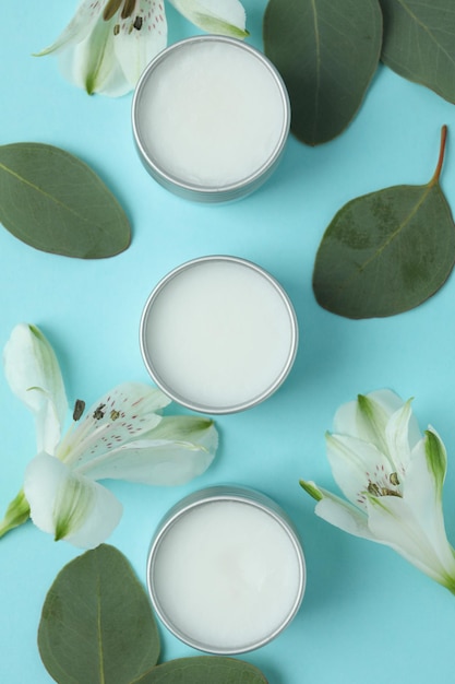 Eco lip balm and flowers on blue background