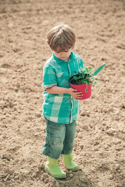 田舎でのエコ生活の瞬間庭に花を植える小さなヘルパー小さな農家の男の子exa