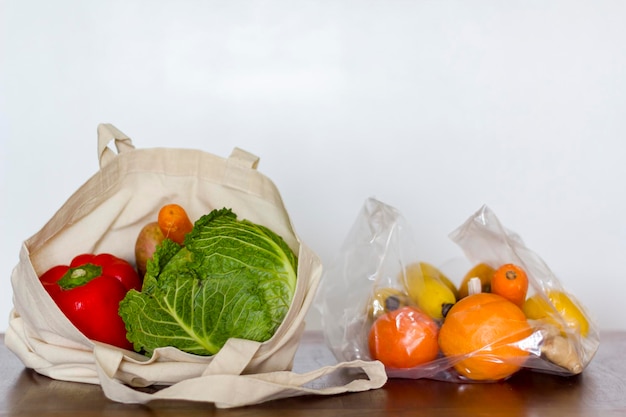 Photo eco reusable bag with vegetables and plastic bag with fruits