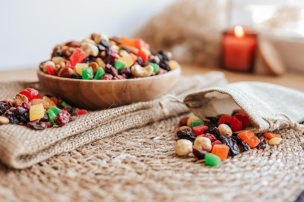 Eco sack with candied fruits spilling out and wooden plate with dried fruits on the table