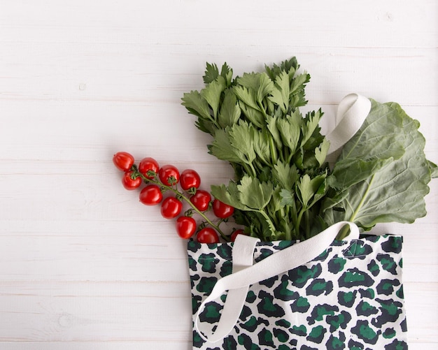 Eco Shopping Bag in trendy luipaardprint met verse biologische groenten en salade op witte houten achtergrond Flat Lay