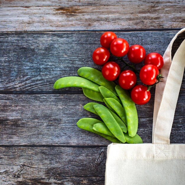 Eco Shopping Bag with fresh organic vegetables and salad on wooden background Flat Lay