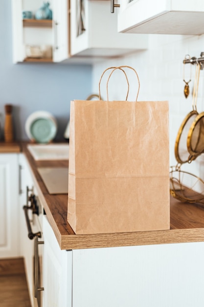 Eco shopping paper bag on the table in modern kitchen. Food delivery or market shopping concept.