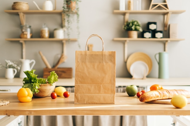 Eco shopping paper bag with fresh vegetables and baguette on the table in kitchen