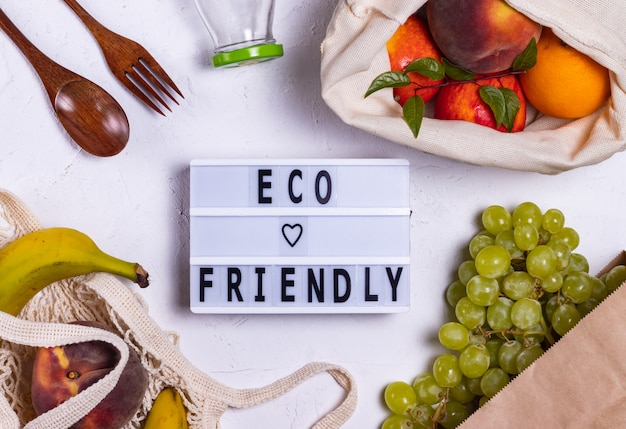 Foto eco-vriendelijk schreef op een bord in de buurt van fruit in eco-tassen