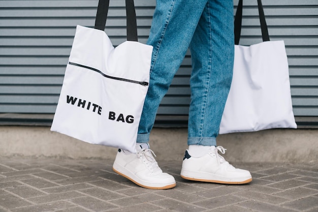 Eco vriendelijke man draagt 2 trendy herbruikbare eco tassen in zijn handen