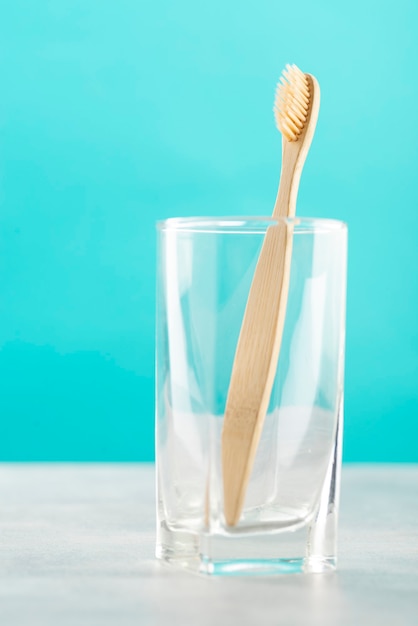 Eco vriendelijke natuurlijke bamboe tandenborstel in een glas op een blauwe ondergrond