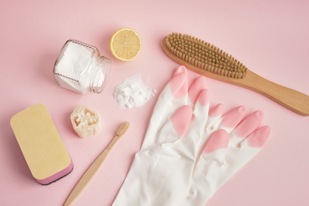 Eco-vriendelijke schoonmaak concept handschoenen houten borstel spons citroen en frisdrank op roze achtergrond