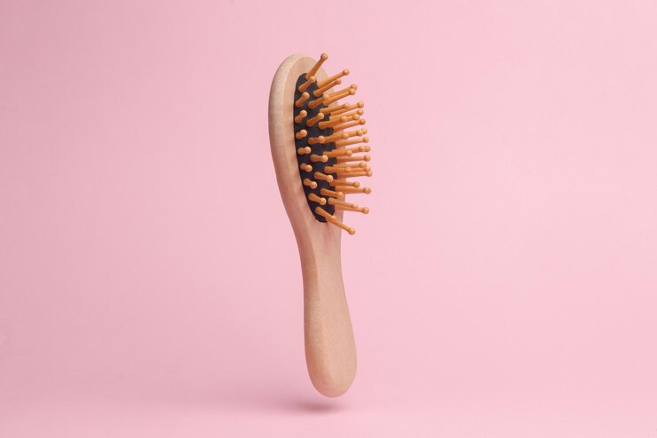 Photo eco wooden hair brush flying in antigravity on pink background with shadow levitation object in the air beauty and fashion concept creative minimalist layout