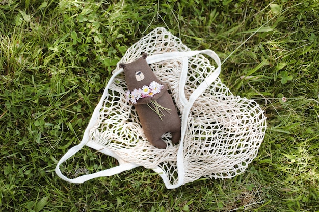 Ecofriendly cute handmade toy bear on grass at sunny summer day