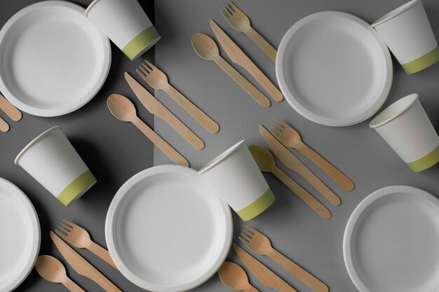 Ecofriendly disposable bamboo wood and paper dishes on a gray background Draped spoons forks knives bamboo bowls with paper cups