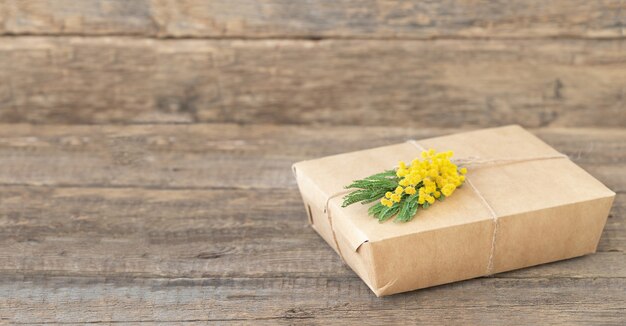 Ecofriendly lunch box with sprig of mimosa on wooden surface