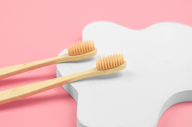 Ecofriendly personal hygiene items Two wooden toothbrushes on a white figured geometric podium No waste no plastic