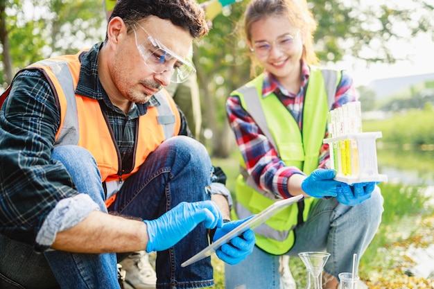 Ecologists use a digital tablet while sample water contaminated from industrial estate