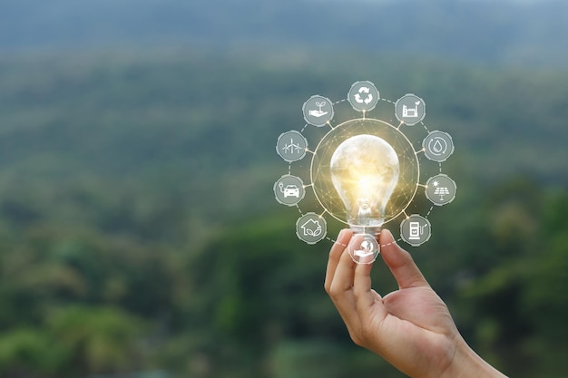 Ecologia e concetto di energia verde mano che tiene la lampadina davanti agli spettacoli di vista sulle montagne