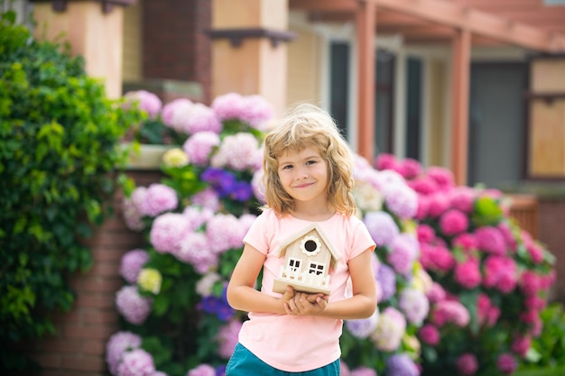 Ecology house in childrens hands against backyard Happy dream home