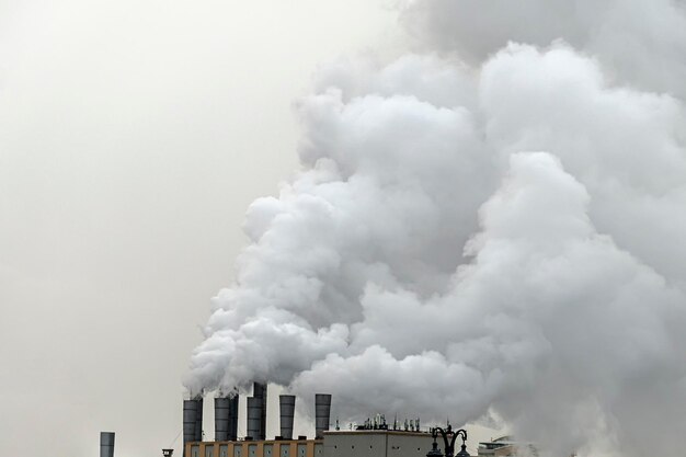 Ecology problem. Smoke from chimneys of heating plant. Air pollution. Factory pipes with smoke, frosty weather, sunrise.