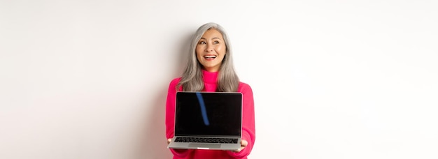 Ecommerce concept happy beautiful asian senior woman with grey hair looking aside and smiling showin