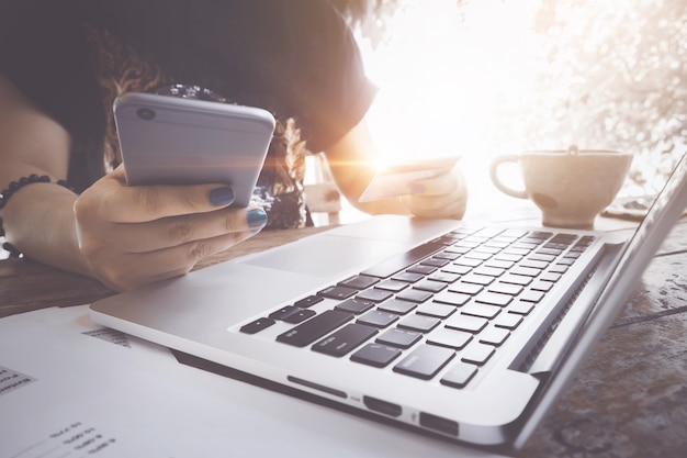 Ecommerce concept. Woman using laptop and credit card for online shopping at coffee shop.