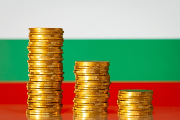 Экономические проблемы в Болгарии Негативный график из золотых монет перед флагом Болгарии