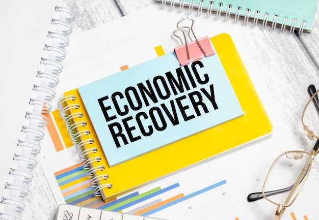 Economic recovery words on blue sticker and pen charts and calculator