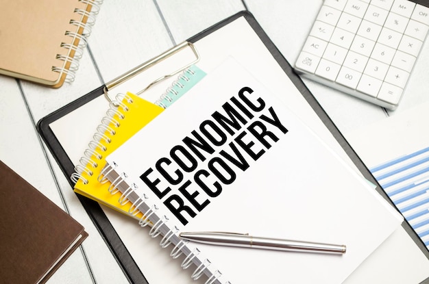 Economic recovery words on notebook and pen charts and calculator