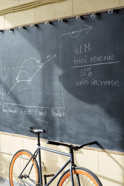 Economical data and graph on blackboard and bicycle of office worker